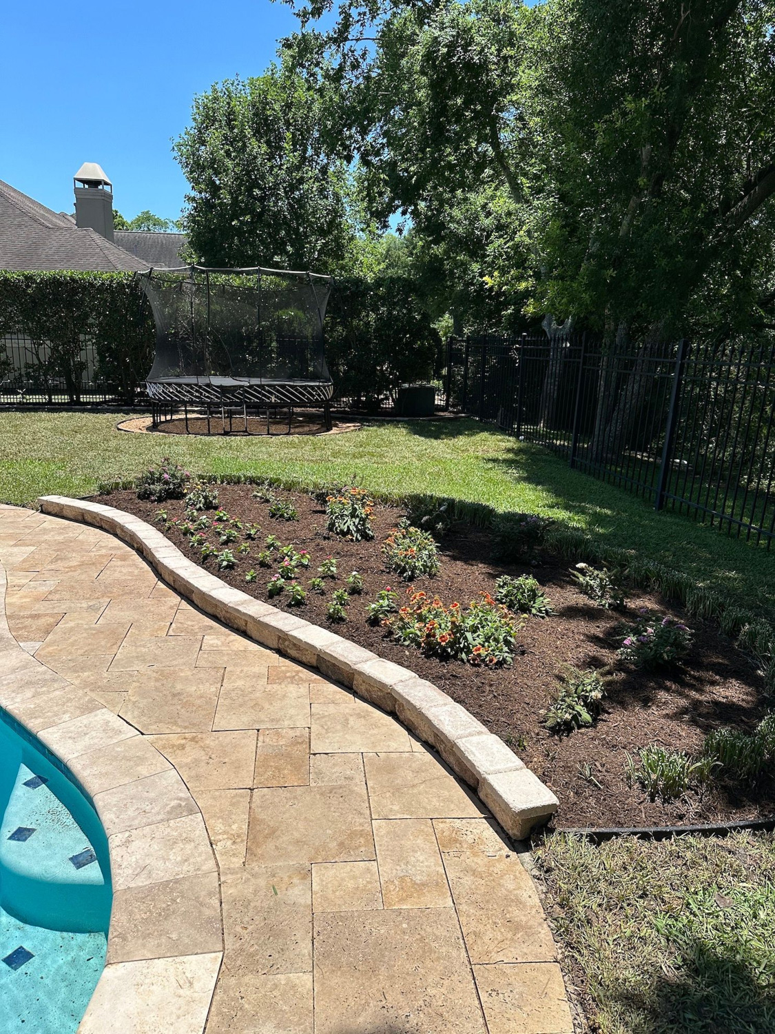 Curved pool coping and paver deck installation with a stone retaining edge