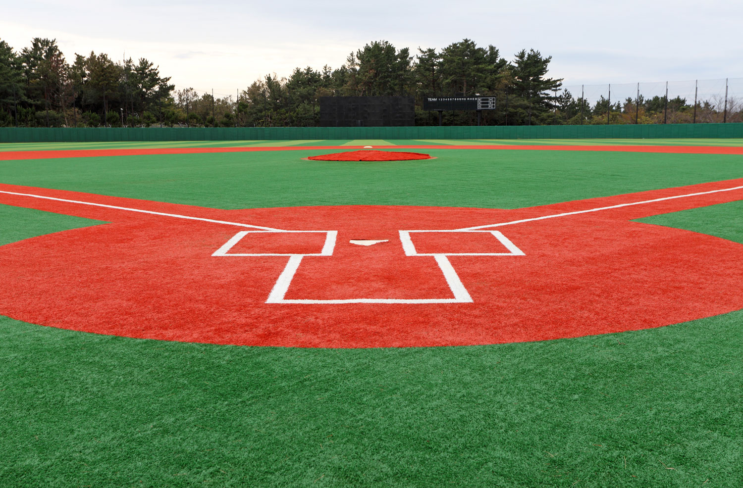 All-turf baseball field with red base paths and green grass turf